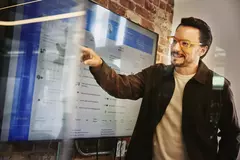 Male standing in front of a screen and pointing at data